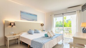 A bedroom with a bed, bedside tables, a desk, and a view of the outdoors. - Hotel Martorell (Ses Salines)