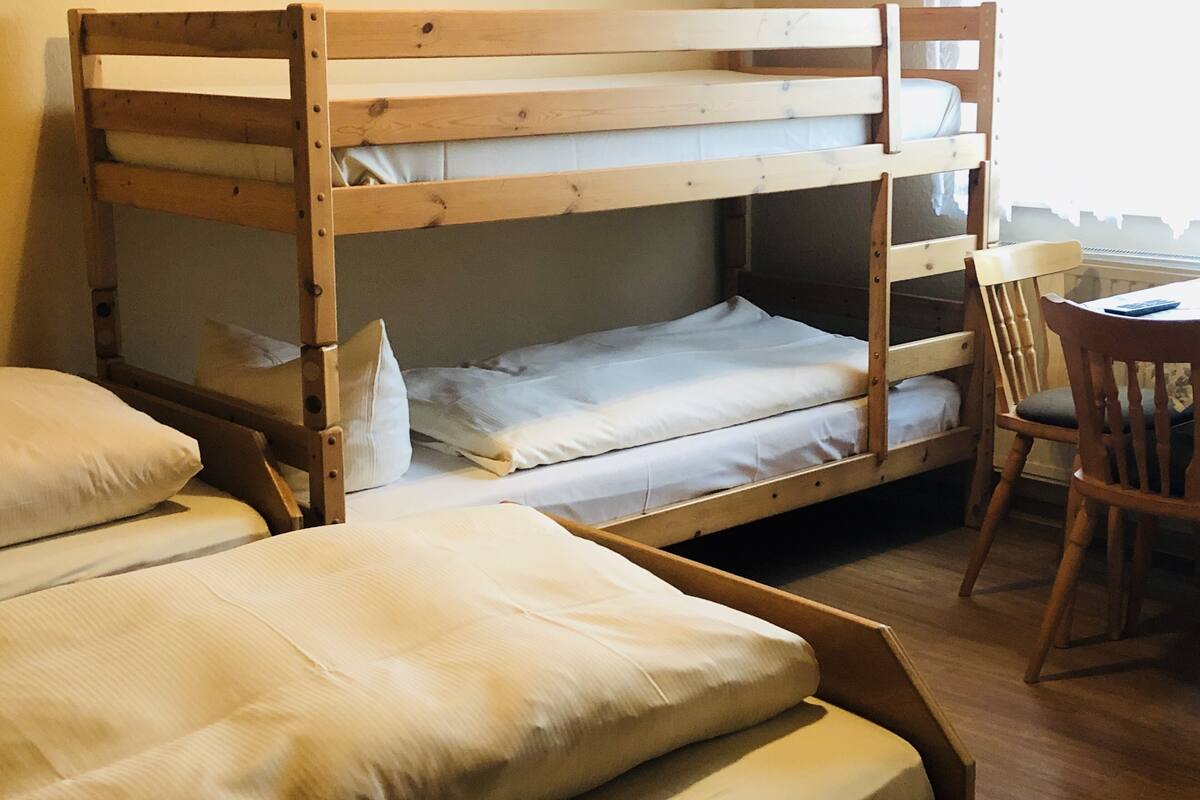 A bunk bed with two levels, a wooden chair, and a small table.