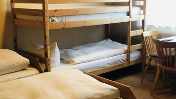 Una cama litera de dos niveles, una silla de madera y una mesita pequeña.