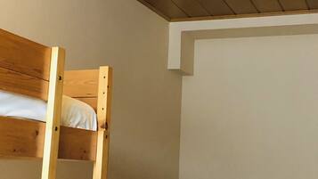 Habitación con literas, techo de madera y una mesita de noche con lámpara.