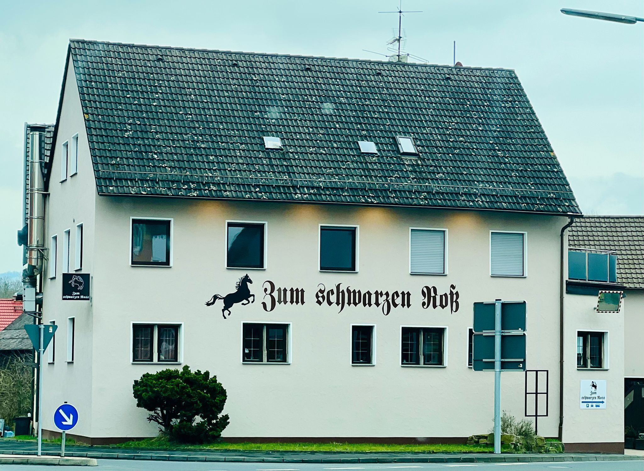 Um edifício com uma placa que diz 'Zum schwarzen Hof' e uma silhueta de cavalo.