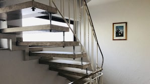 Una escalera de caracol con barandilla de metal y un cuadro en la pared.