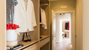 Un armario de madera con ropa colgada, una camisa blanca y un arreglo floral rojo.