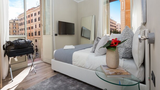 Habitación de hotel moderna con cama, una mesa de vidrio, televisor y vista a edificios.