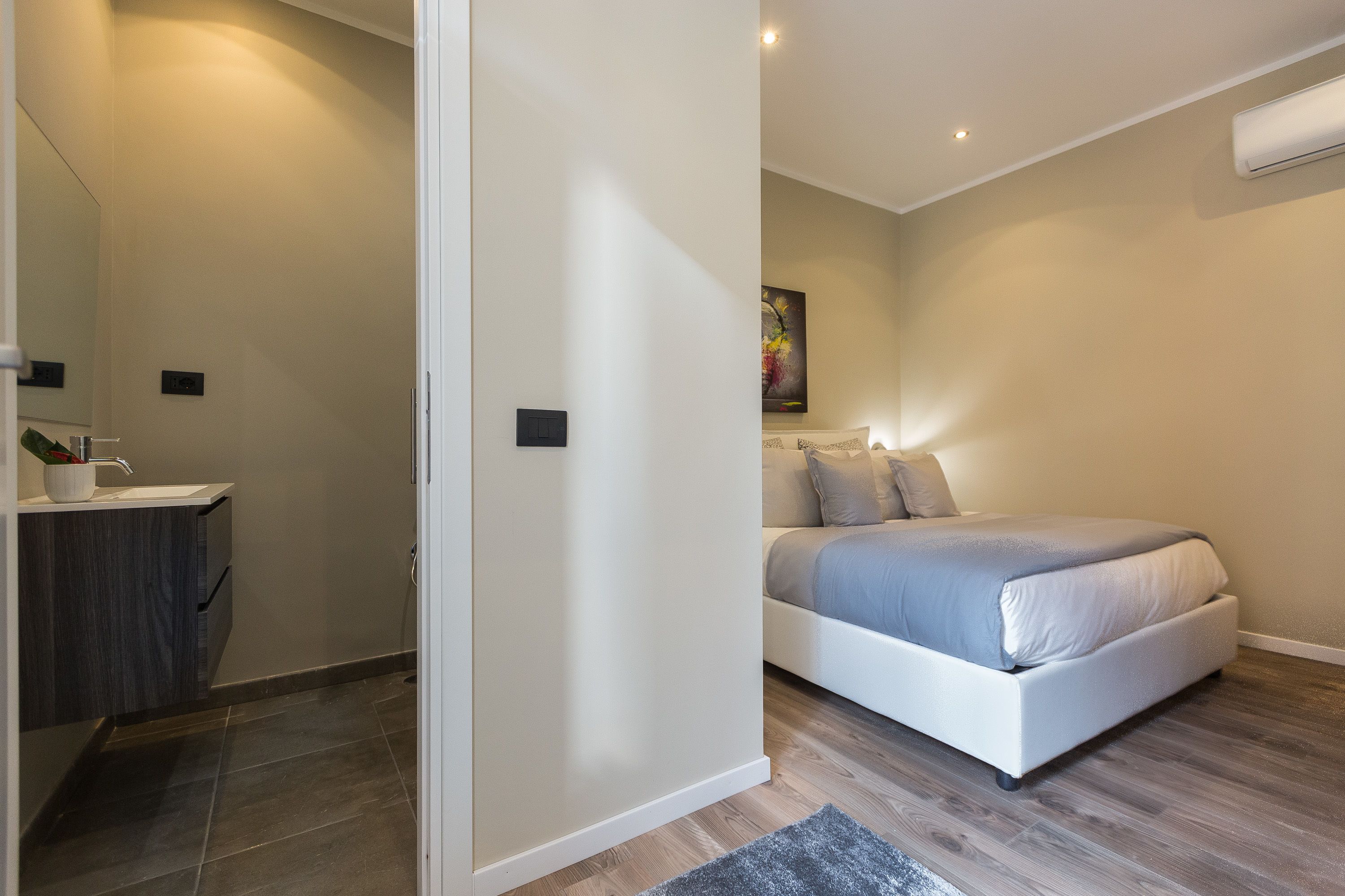 A bedroom with a bed, bedside table, and a wall-mounted air conditioner.
