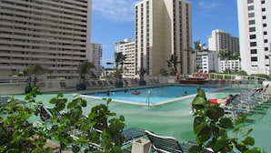 A hotel pool area with multiple swimming pools, surrounded by tall residential buildings. - HAWAII  2 MIN FROM THE BEACH (Honolulu)