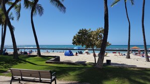 A beach with palm trees, a blue tent, and people relaxing. - HAWAII  2 MIN FROM THE BEACH (Honolulu)