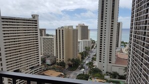 A high-rise building complex with multiple floors, a street with cars, and a view of the ocean. - HAWAII  2 MIN FROM THE BEACH (Honolulu)