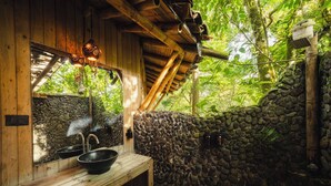 Una cabaña de madera con un muro de piedra, un banco de madera y un lavabo.
