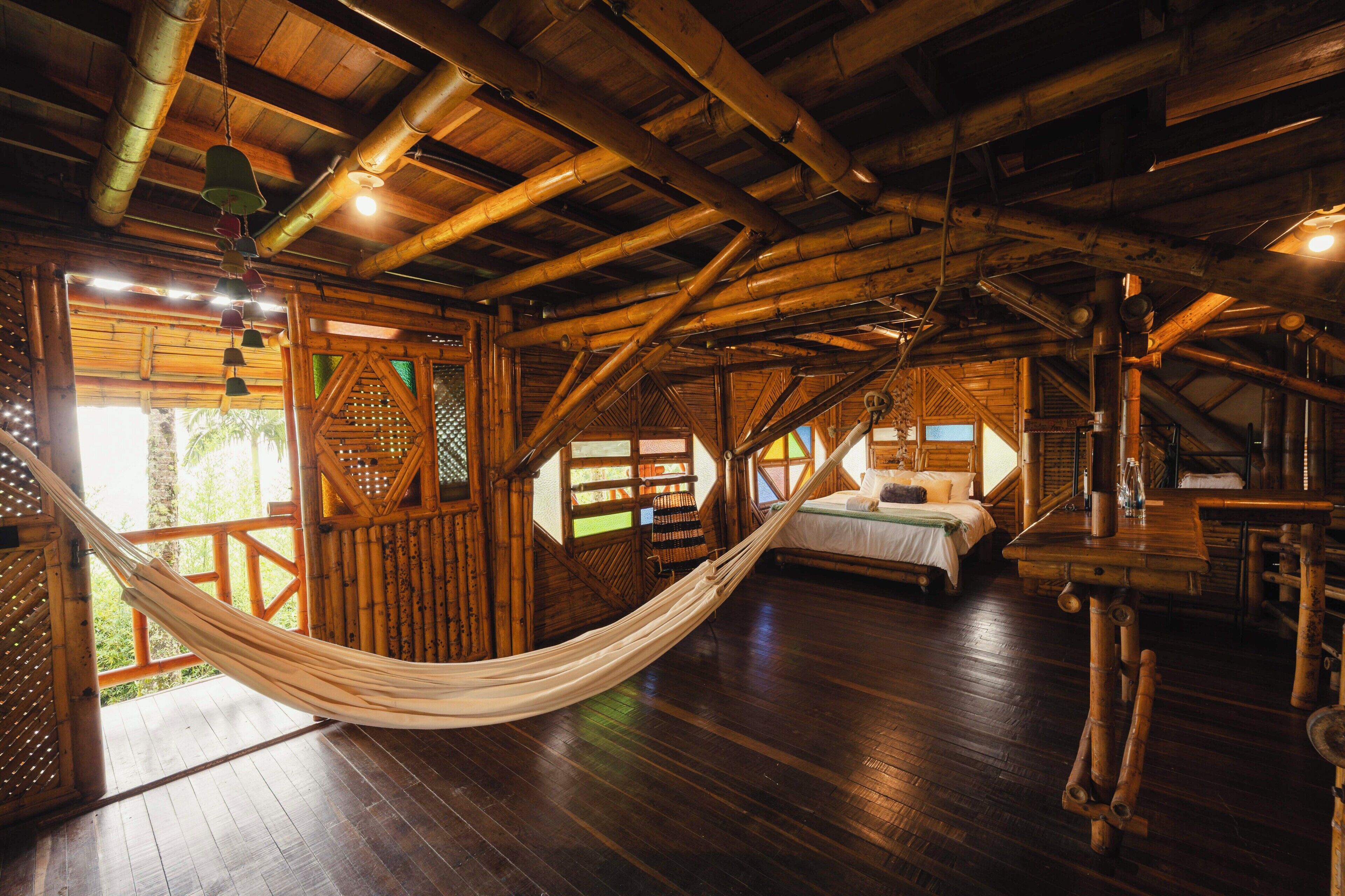 Un interior de madera con una hamaca, una cama y una escalera.