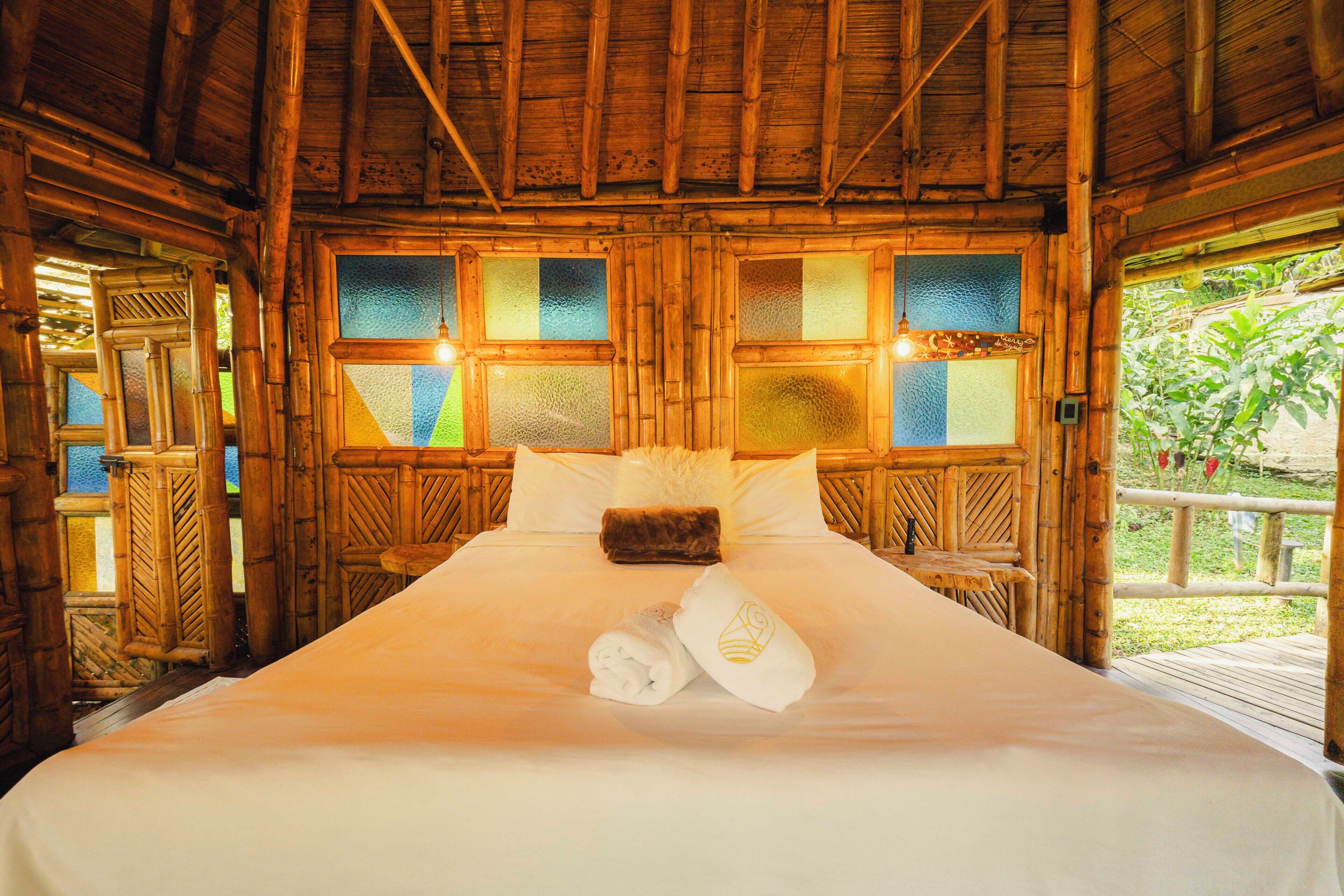 A wooden room with a bed, windows, and a view of greenery.