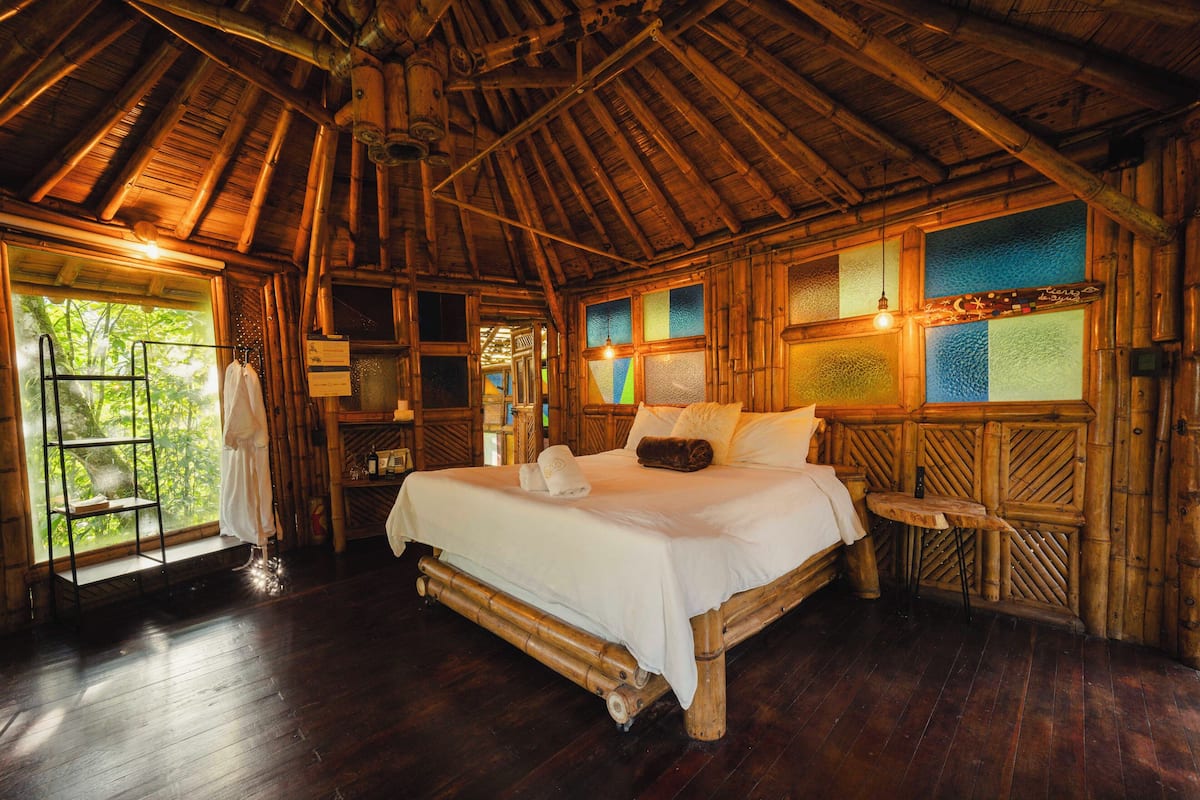 A wooden room with a bed, a window, and a shelf.