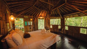Una habitación de madera con una cama, una silla y ventanas grandes.