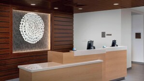 A reception desk with a modern design, featuring a wooden panel wall and a decorative circular wall piece.