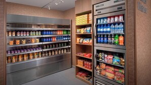 A self-service beverage and snack vending area with multiple shelves stocked with various drinks and snacks.