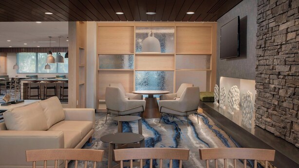 A modern lounge area with a sofa, chairs, a round table, and a patterned carpet.