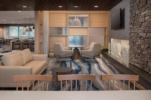 Ein moderner Lounge-Bereich mit einer Couch, Sesseln, einem runden Tisch und einem gemusterten Teppich.