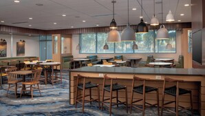 A modern restaurant with a bar area, booths, and high tables.