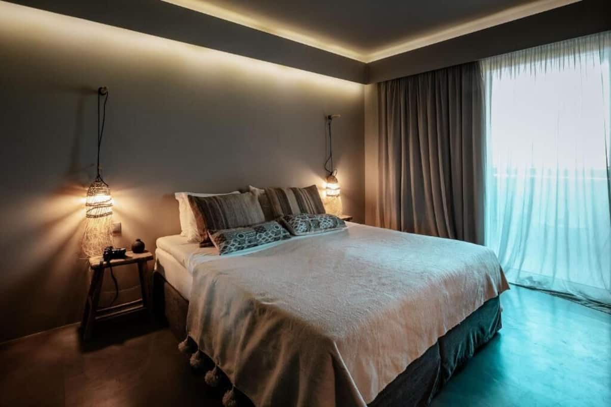 A neatly made bed with a light-colored duvet, two bedside lamps, and a nightstand with a small item on it.