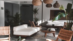 Un saló modern amb un sofà blanc, cadires de vimet, una taula de centre i plantes en testos.
