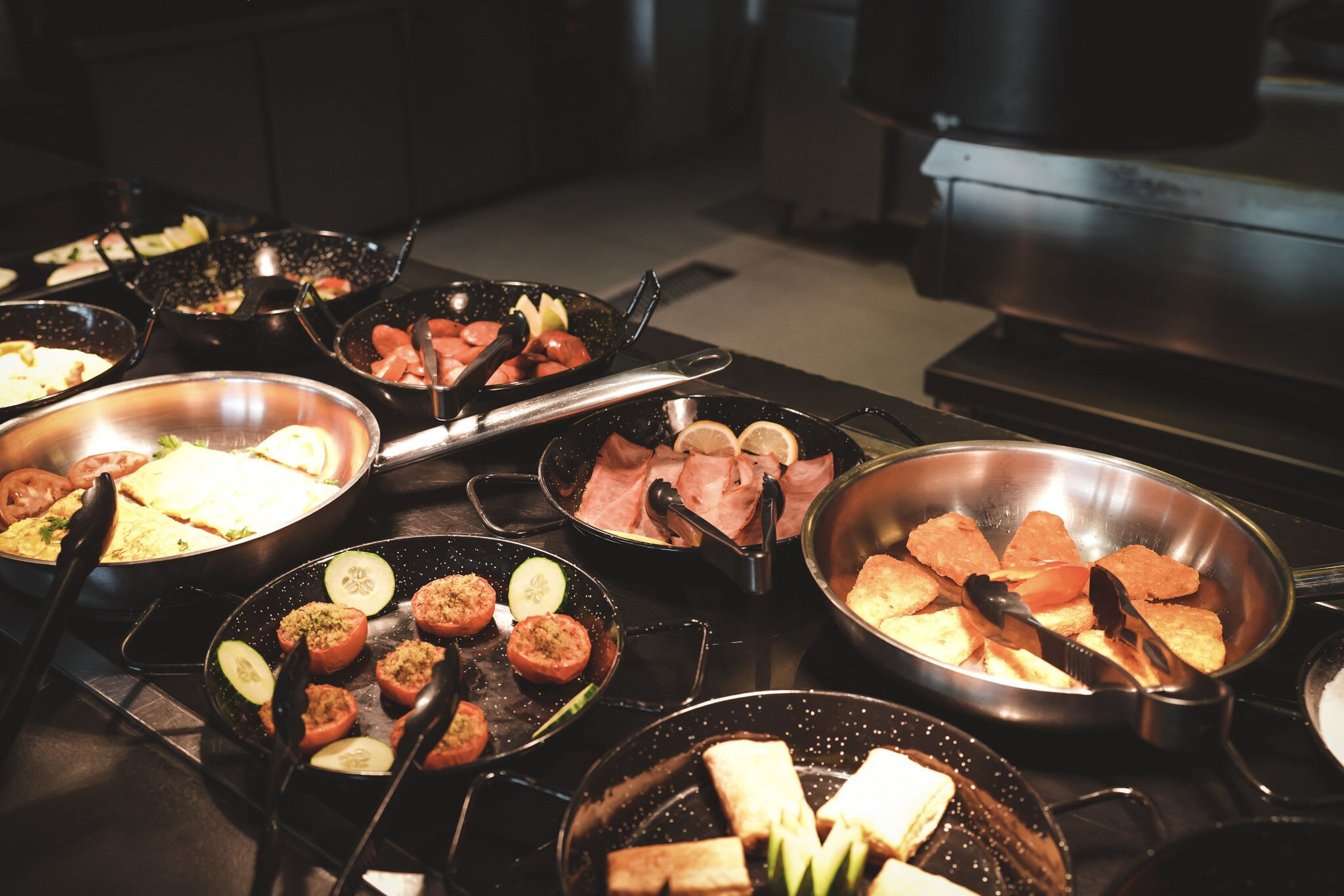 A kitchen with multiple pans on a stove, some containing food items.