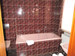 Et badeværelse med badekar, toilet og håndvask.