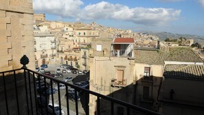 Paisagem urbana com edifícios históricos, uma torre de pedra imponente e céu claro.