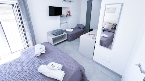 Quarto de hotel moderno com duas camas, televisão de tela plana, espelho e escrivaninha.