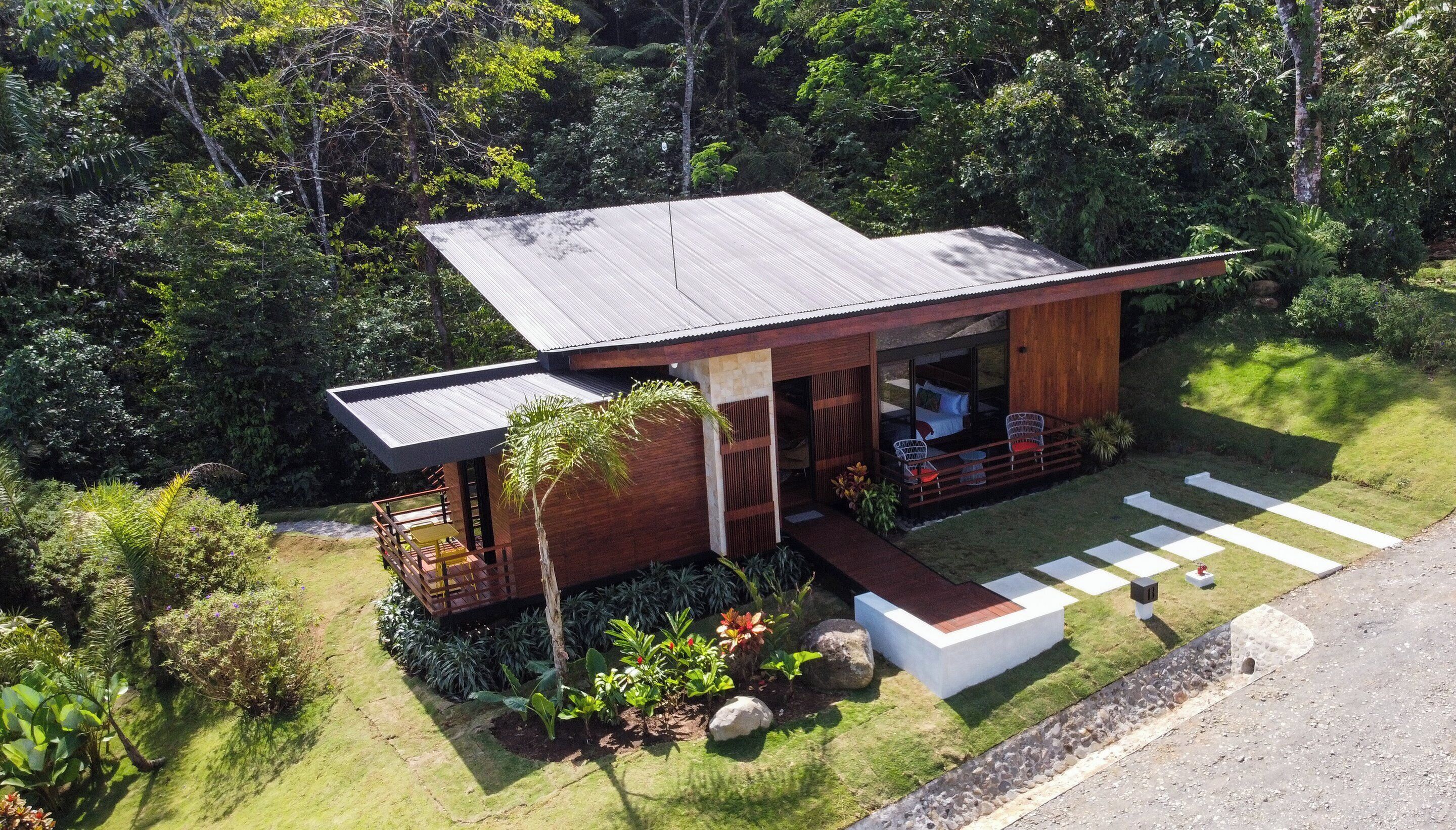A modern house with a large deck, surrounded by lush greenery.
