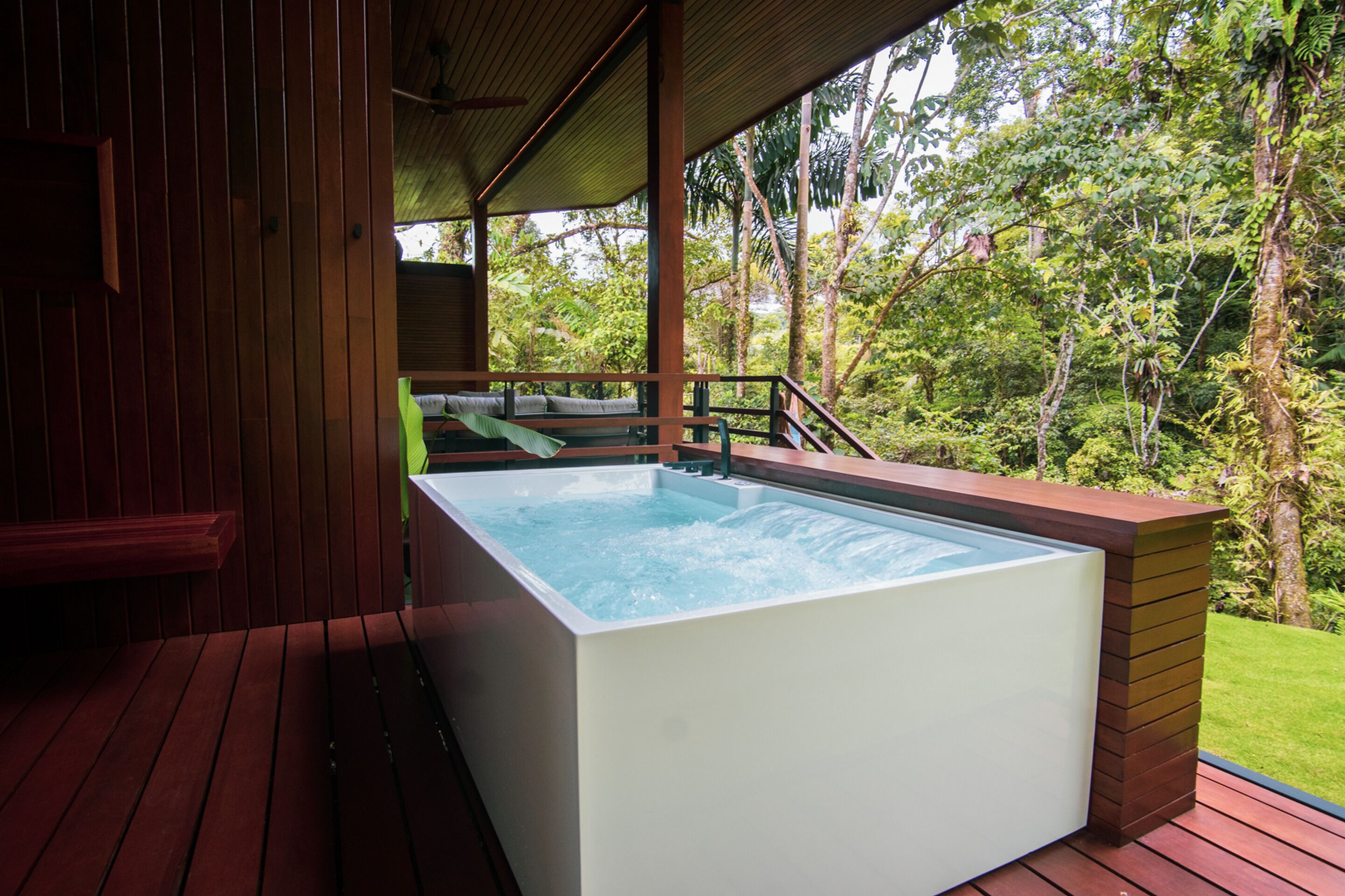 A hot tub on a wooden deck with a view of lush greenery.