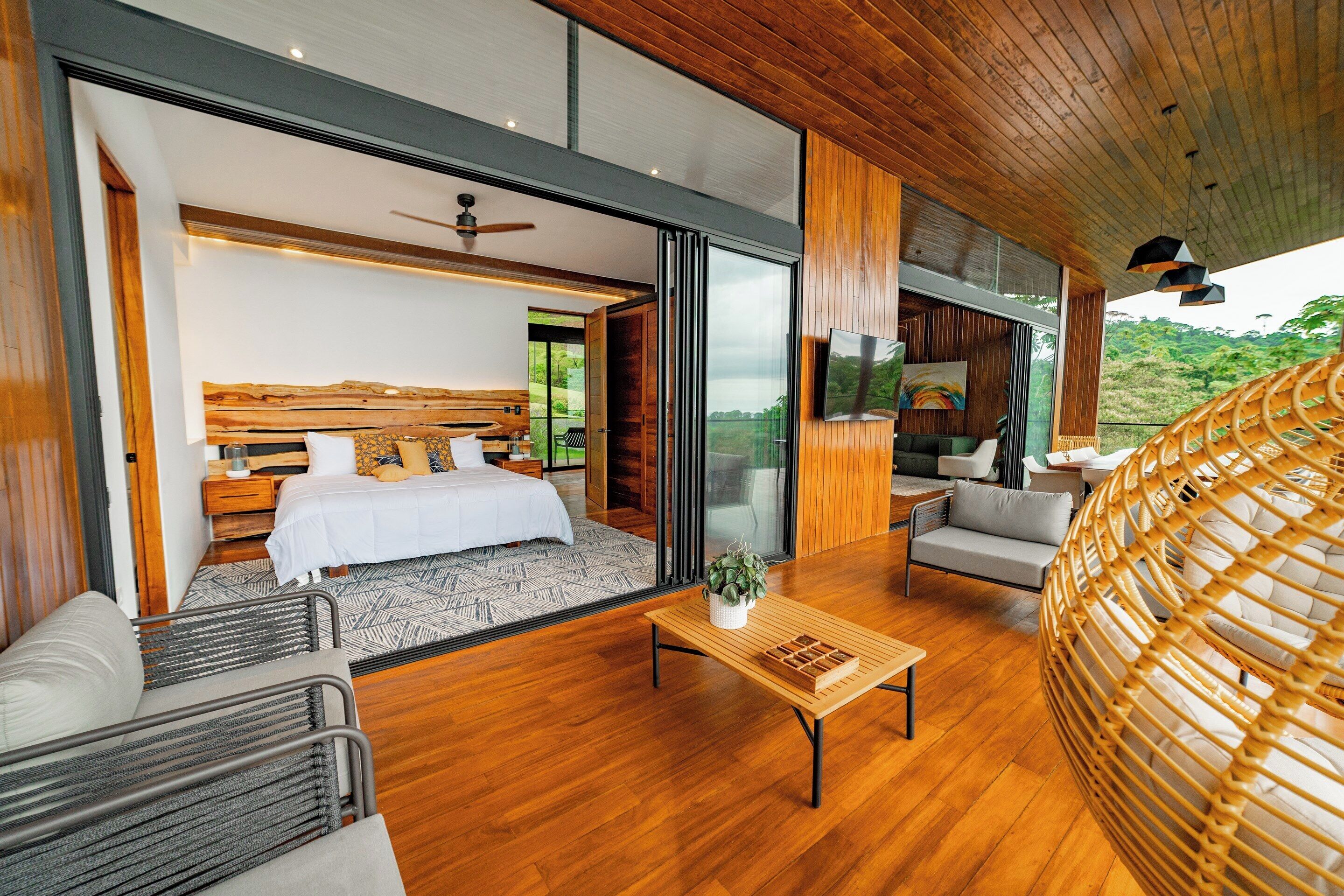 Un dormitorio moderno con una cama grande, un sofá, una mesa de centro y vistas al exterior.