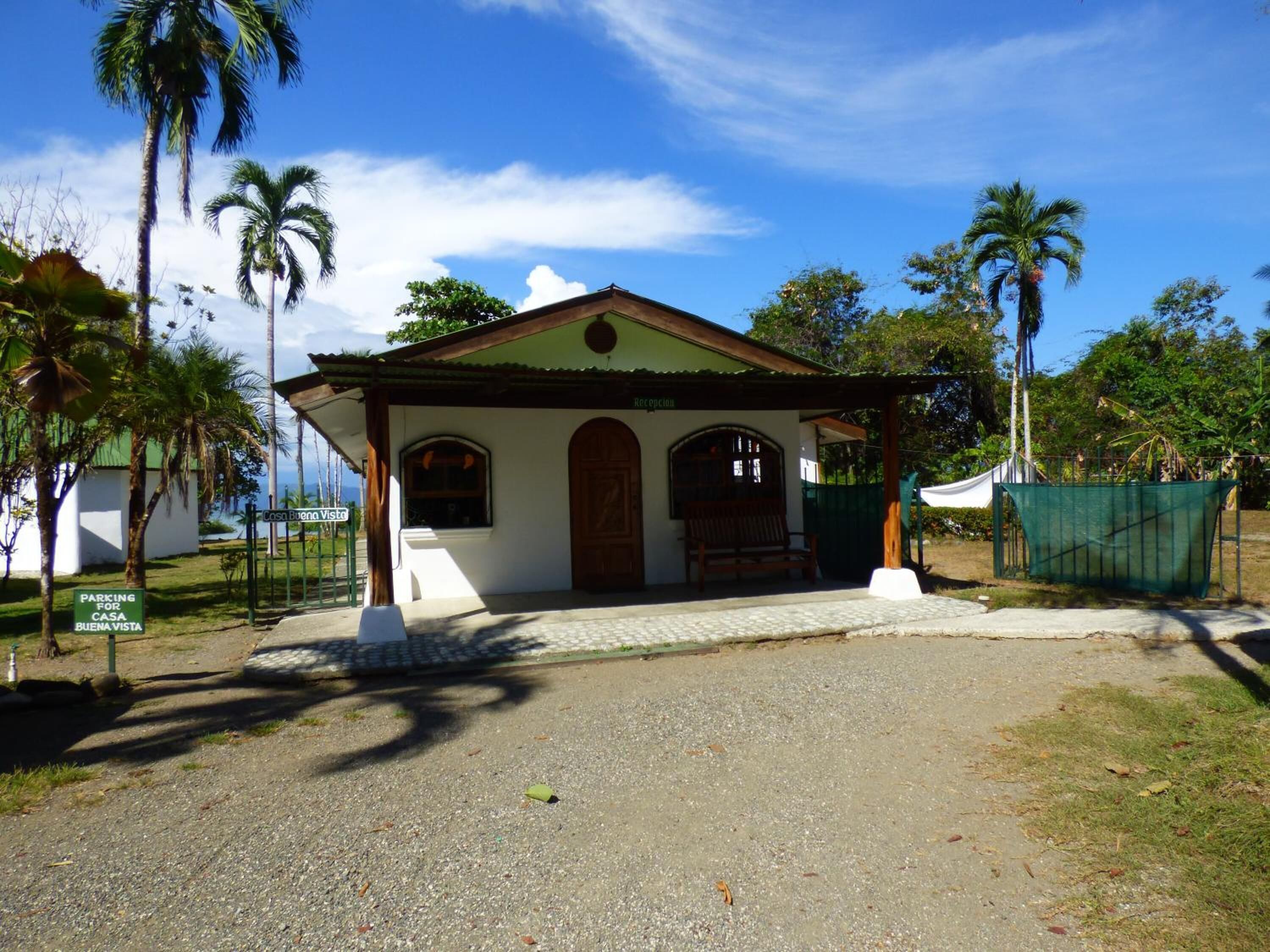 A small building with a porch, a bench, and a sign indicating parking for Casa Buena Vista.