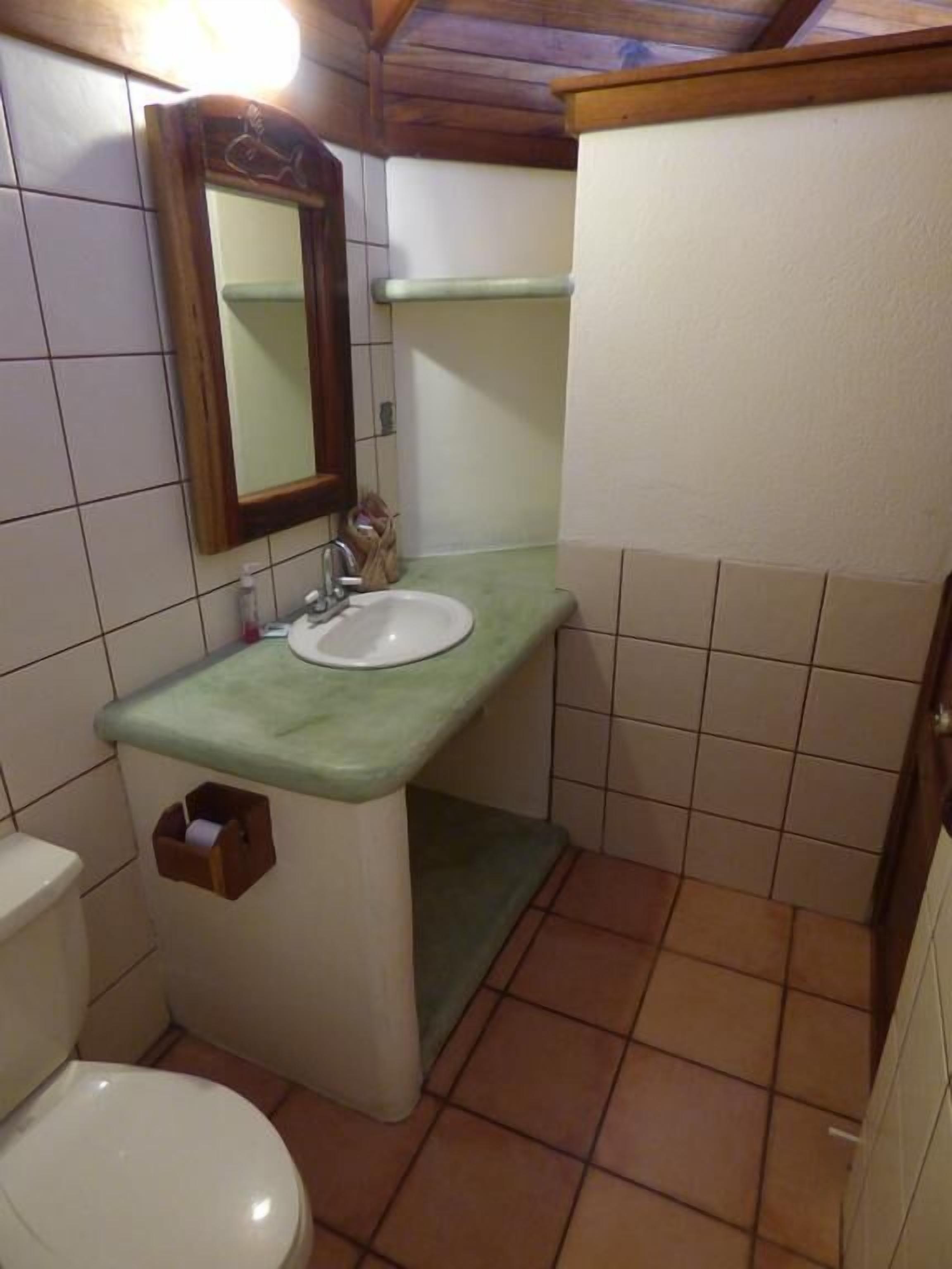 Un baño pequeño con inodoro, lavamanos y espejo.