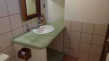 Un baño pequeño con inodoro, lavamanos y espejo.