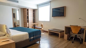 A hotel room with a bed, desk, chair, and a TV on the wall. - Xima Lima San Isidro (Lima)