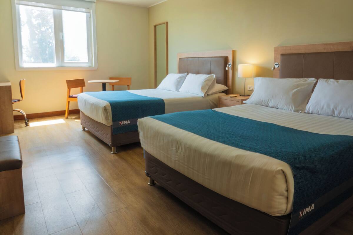Ein Hotelzimmer mit zwei Betten, einem Schreibtisch und einem Stuhl.