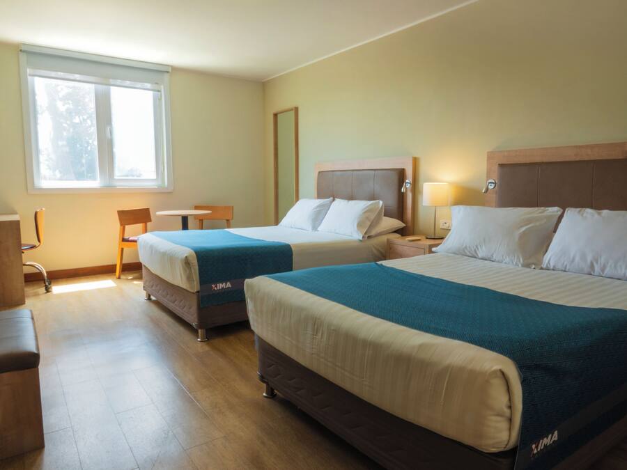 A hotel room with two beds, a desk, and a chair.