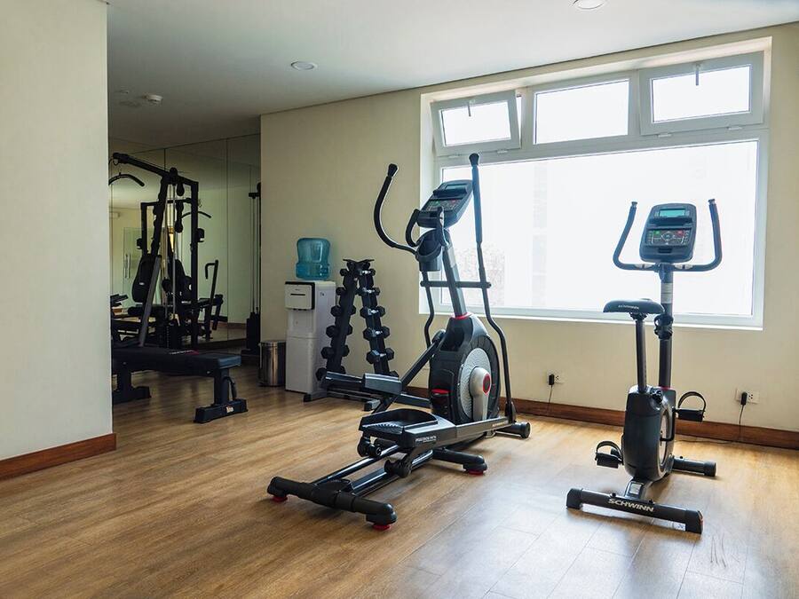 A home gym with exercise equipment including a treadmill, elliptical, and weight machines.
