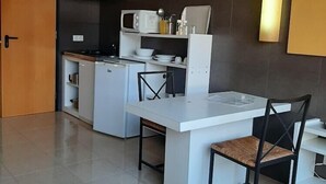 Une cuisine moderne avec un plan de travail blanc, des chaises noires et un four à micro-ondes.