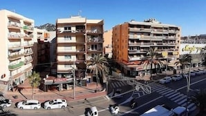 Un immeuble à plusieurs étages doté de balcons, d’un parking et donnant sur la rue.