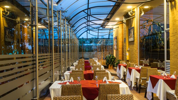 Un restaurante con mesas dispuestas para comer, techo de vidrio y plantas de interior.