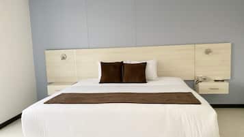 Quarto moderno com uma cama grande, cabeceira de madeira, mesas de cabeceira e um telefone fixado na parede.