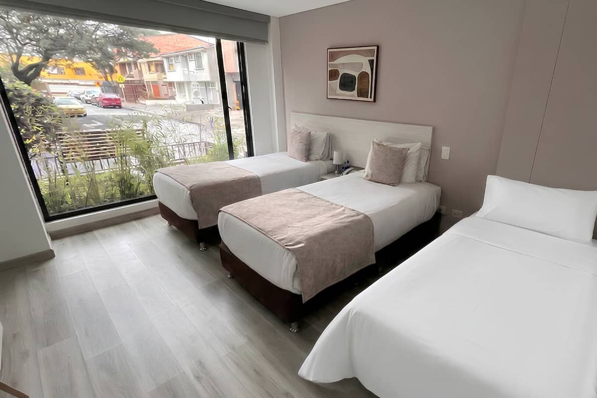 A hotel room with two beds, a large window, and a view of the outside.