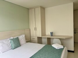 Una habitación de hotel con una cama, un escritorio y un armario.