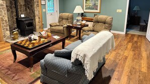 A living room with a stone fireplace, two armchairs, a sofa, a coffee table, and a chessboard. - Creekside in the Smoky Mtns.
has a rejuvenating quality. Something we all need! (Otto)