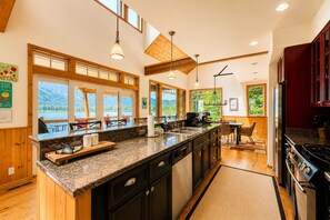 Una cocina con encimera de granito, armarios de madera y vista al lago.