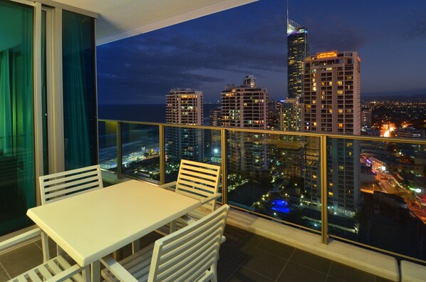 Enjoy breathtaking city views from this balcony with a table and chairs.