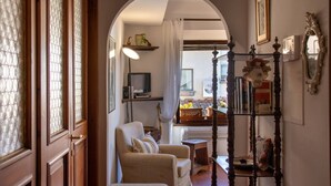 A cozy living room with a wooden door, a chair, a small table, and a bookshelf. - Charming, Romantic Apartment,  50mt from Ponte Vecchio, AC, WIFI, LIFT (Florence)