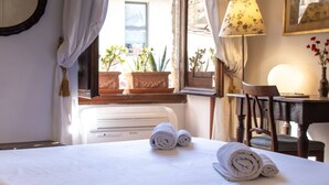 A hotel room with a bed, a desk, a chair, a lamp, and a window with curtains. - Charming, Romantic Apartment,  50mt from Ponte Vecchio, AC, WIFI, LIFT (Florence)