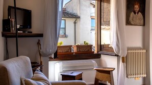 A cozy living room with a television, a radiator, a window with curtains, and a painting on the wall. - Charming, Romantic Apartment,  50mt from Ponte Vecchio, AC, WIFI, LIFT (Florence)